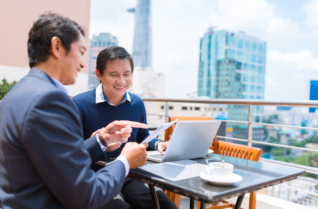 Man showing document to his colleague while they are drinking coffee in the rooftop cafe